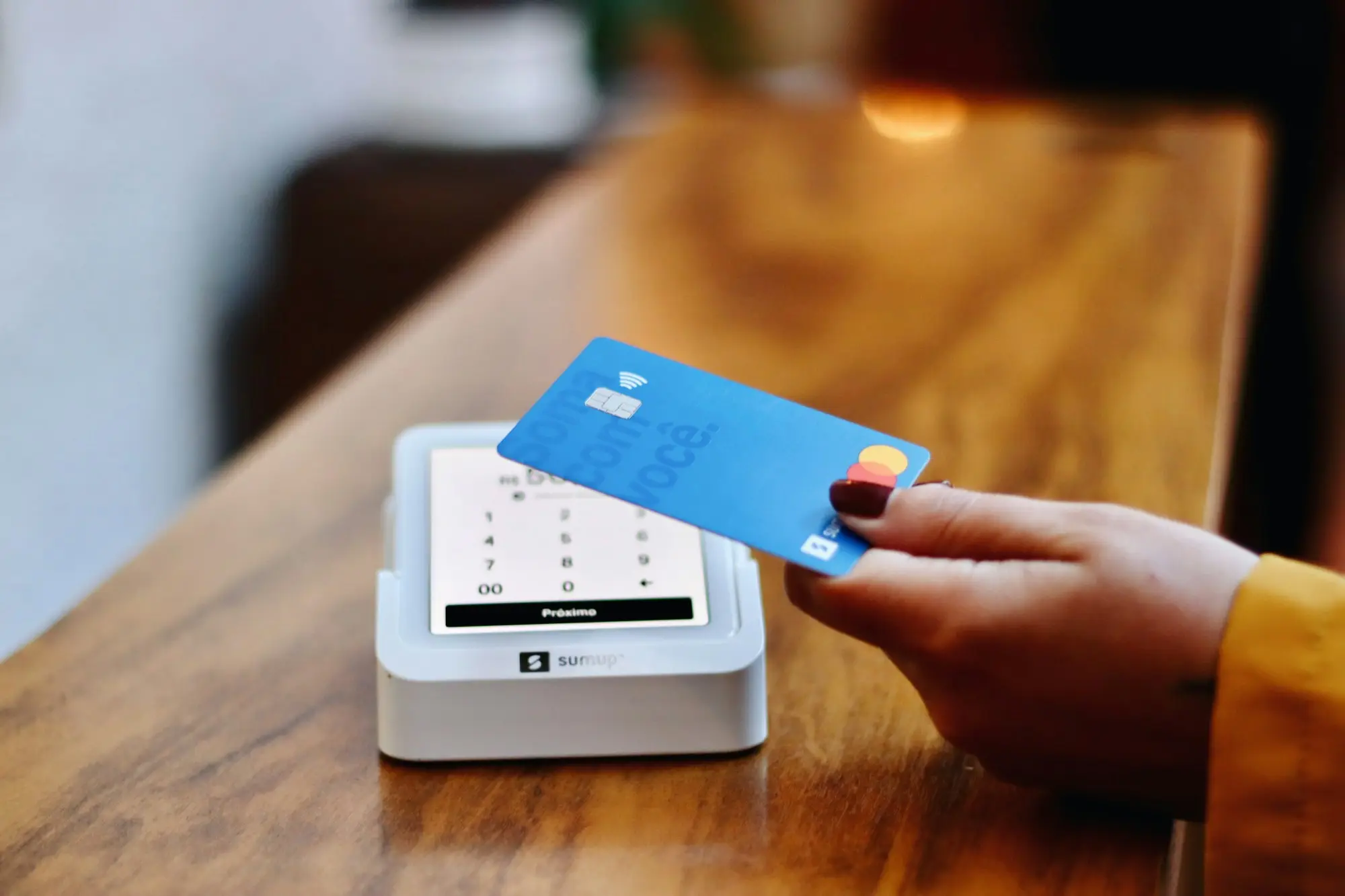Customer tapping a card on a payment terminal at a retail counter