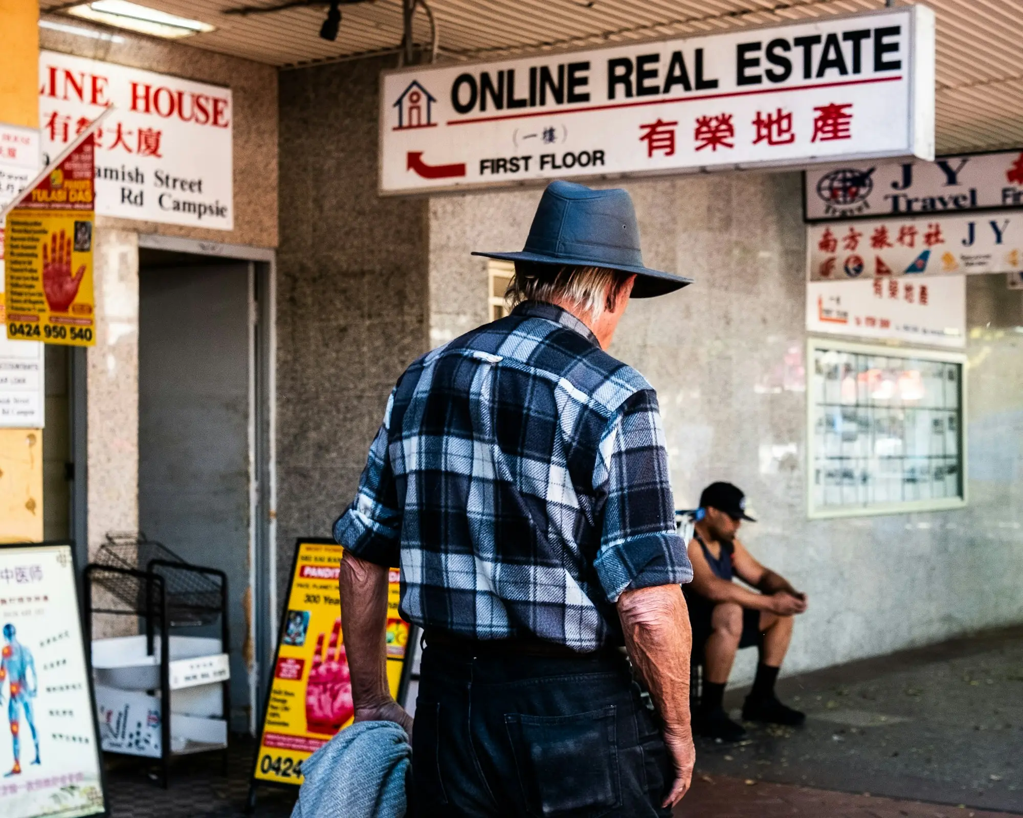 Man in a hat walking past shopfronts in Sydney