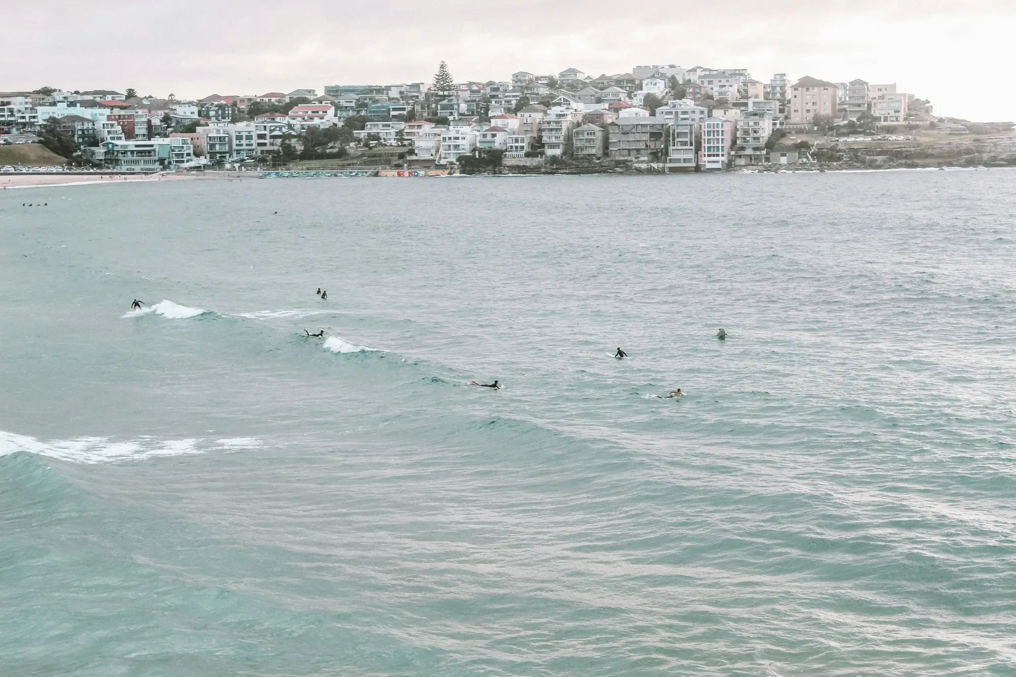 Bondi Beach waves and surfers with shops along the shoreline