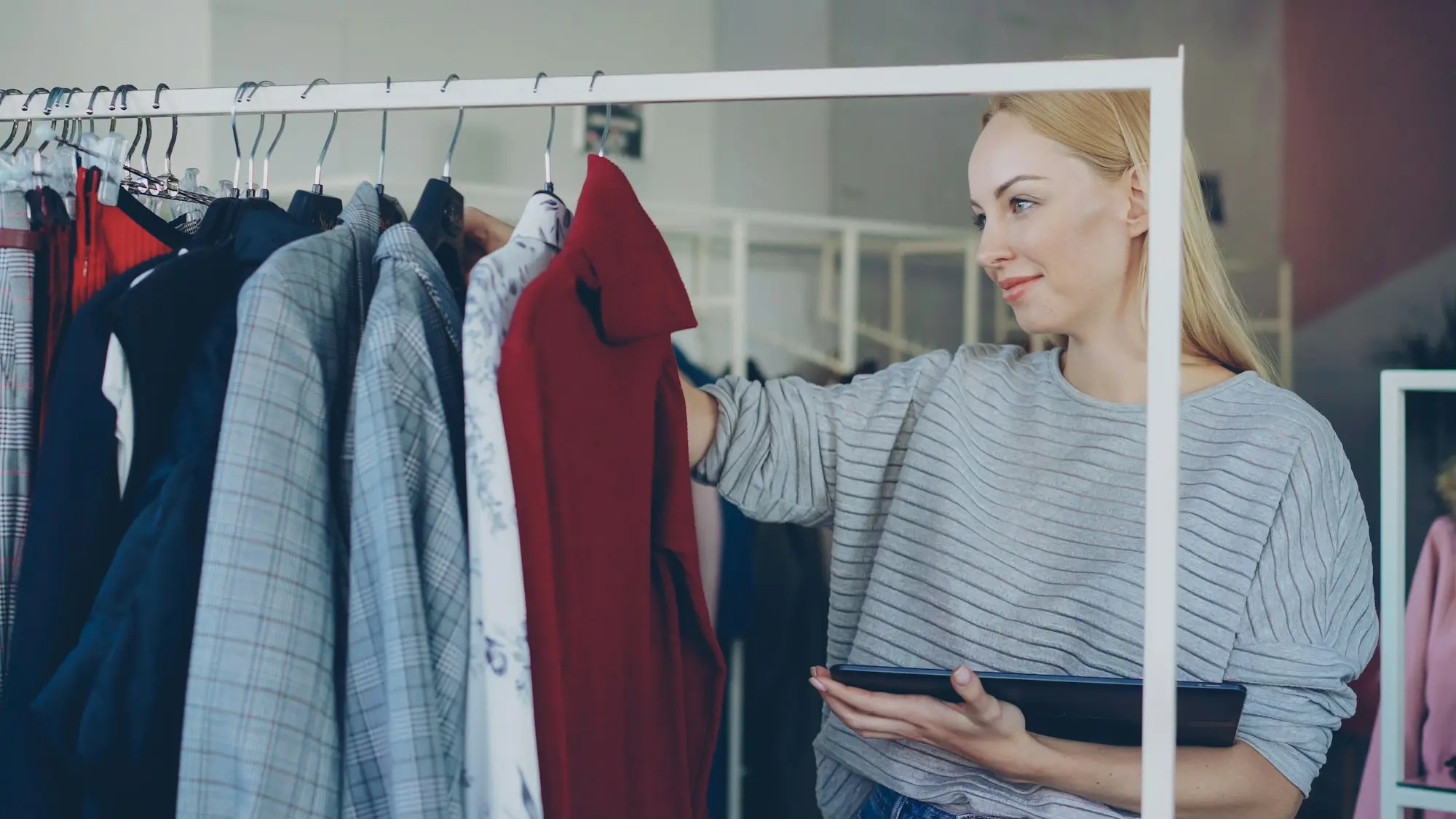 Business owner checking clothing stock on warehouse rails